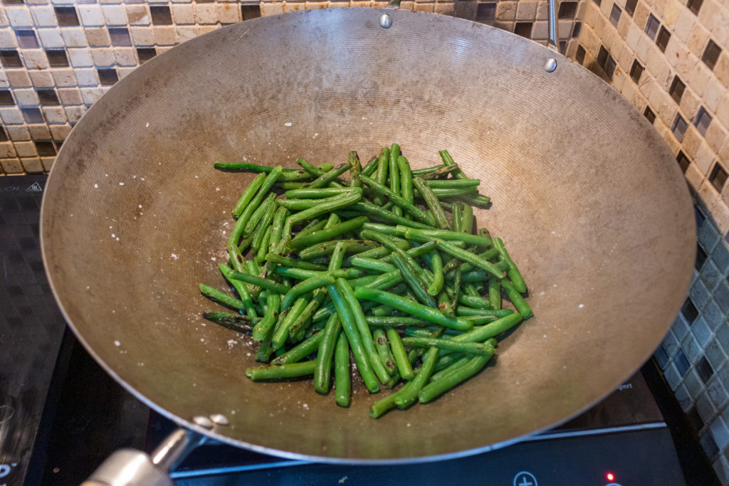 Cook green beans on low heat in a dry pan until blistered