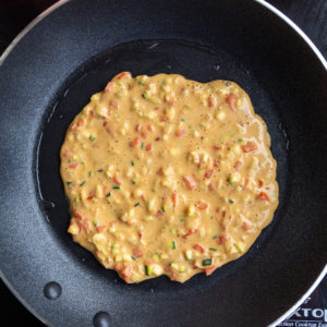 Spread savory chickpea flour pancake batter in a thin layer