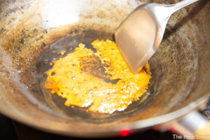 To make caramel for red braised pork, add sugar to hot oil and stir continuously