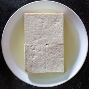 Press medium tofu with a weighted sheet tray to get firm tofu