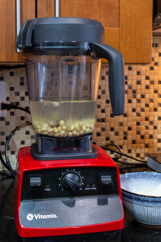 Vitamix blender with soy milk ingredients (steamed soy beans, water, ginger, medjool date, salt)